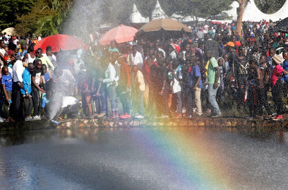People queue to drink fresh water from a burst pipe at Uhuru Park during Christmas Day Celebrations in Nairobi, Kenya December 25, 2018.