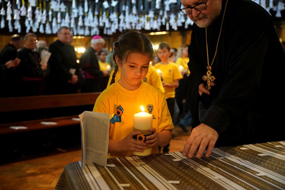 Children from St Mary's Ukrainian School lighting some of the 52 candles - one for each week of the war - during an ecumenical prayer service at the Ukrainian Catholic Cathedral in London24 February 2023