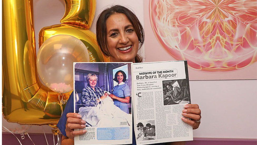 A midwife holding an old photograph in front of balloons