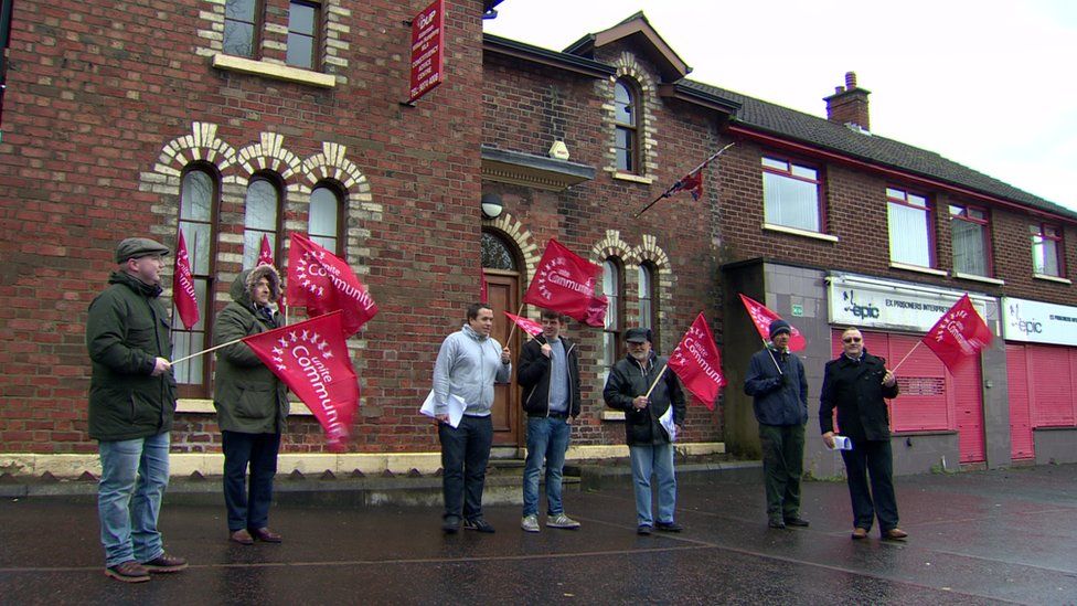 Protesters wave Unite trade union flags outside a DUP office on Belfast's Shankill Road