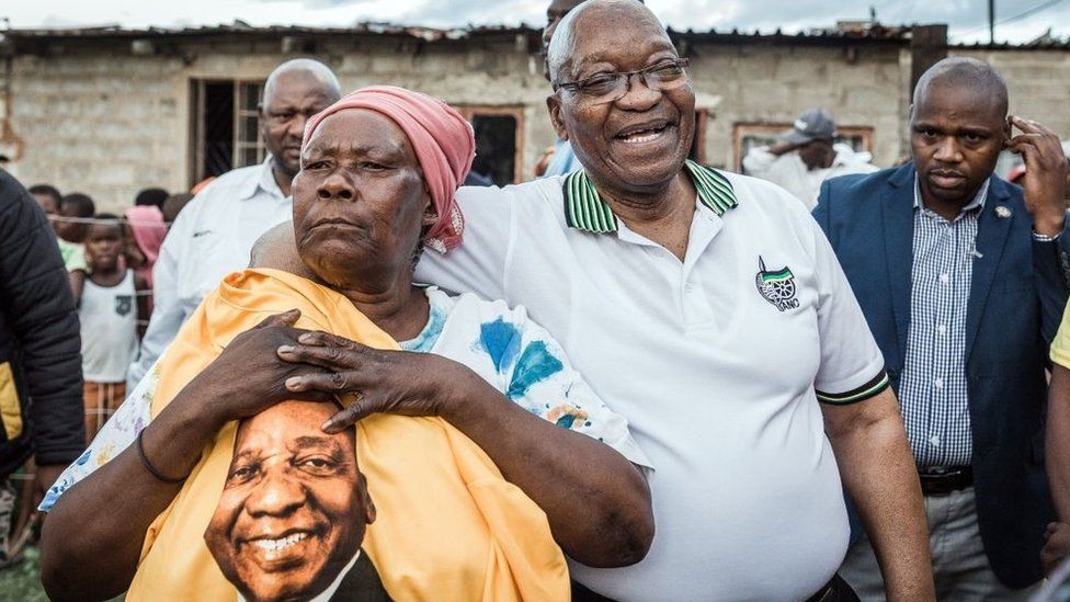 Former South African President and former president of the ruling party African National Congress (ANC) Jacob Zuma (2ndR) is held tightly by ANC supporter Maria Mandweni during a door to door campaign visit in Shakaskraal township, on April 16, 2019