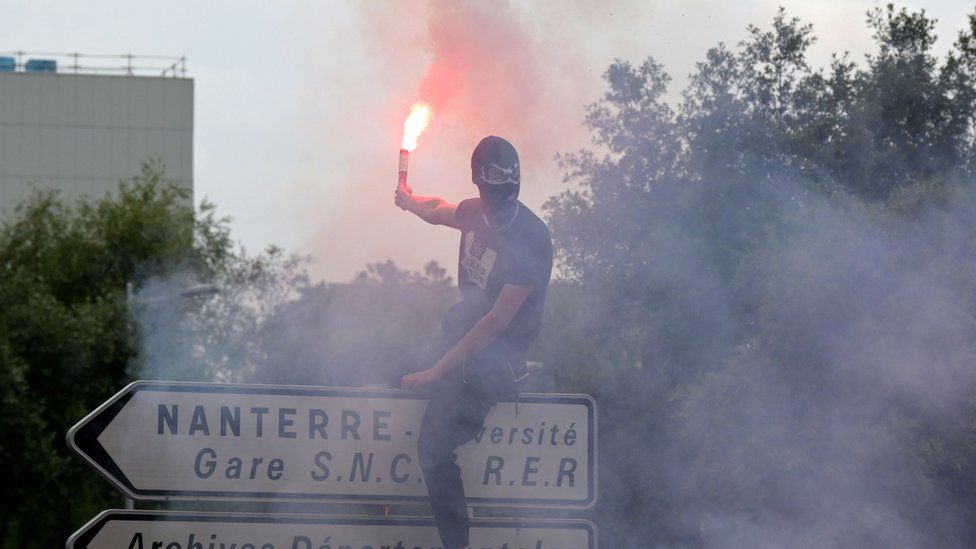 Протестующий в маске с сигнальной ракетой в Нантере