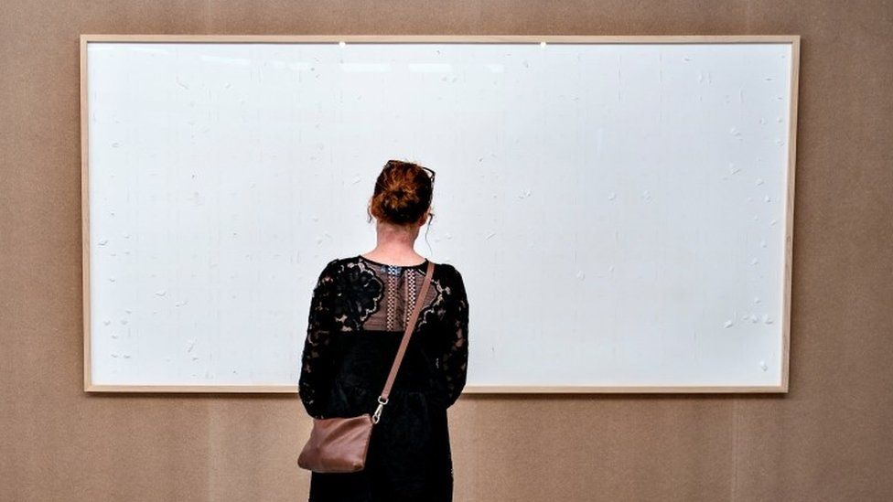 A woman looks at an art installation titled Take the Money and Run by Danish artist Jens Haaning