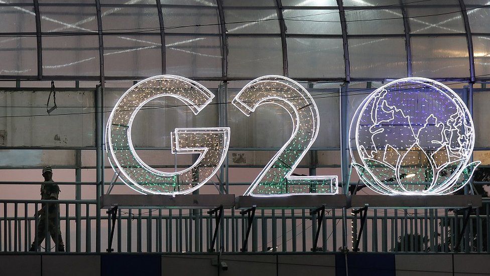 A security personnel stands guard near an illuminated G20 logo ahead of the upcoming G20