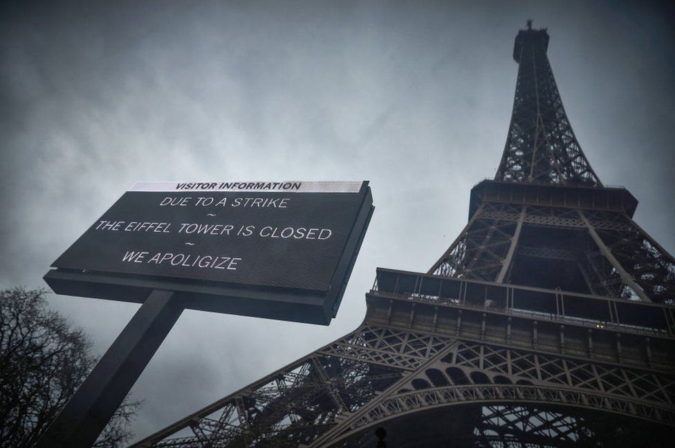 A board informs visitors that the Eiffel Tower, viewed in the background, is closed as staff go on strike. 19 February 2024