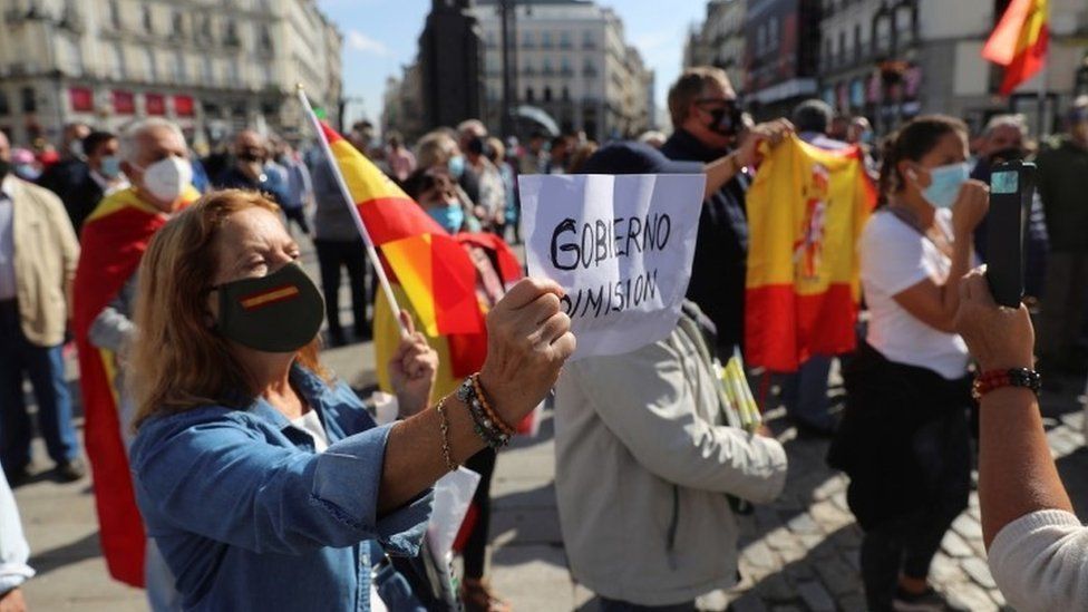A demonstrator holds a poster reading "Government Resignation" during a protest against coronavirus restrictions in Madrid