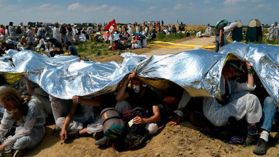 Activists shielding themselves from the sun using a foil blanket