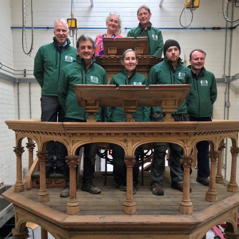 The South West College students and staff who restored the pulpit stand inside it