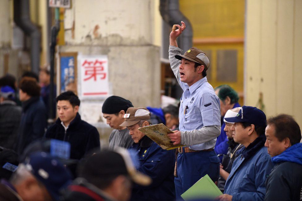 An auctioneer calls for bids at the start of the first auction of the year of frozen tuna at the Tsukiji fish market in Tokyo, Japan, 5 January 2017
