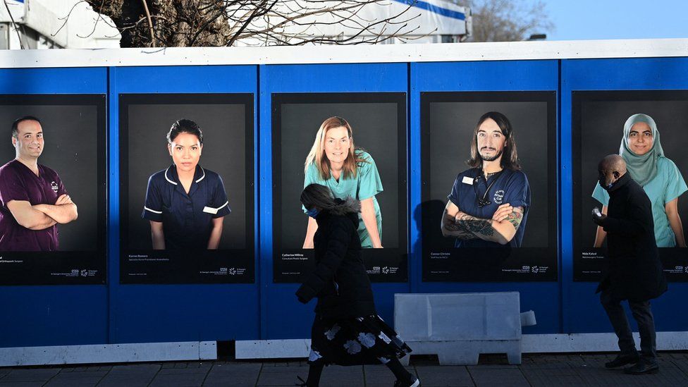 NHS staff posters on a wall showing people in different uniforms