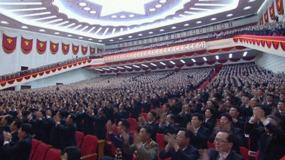 North Korean delegates watch a speech by Kim Jong-un