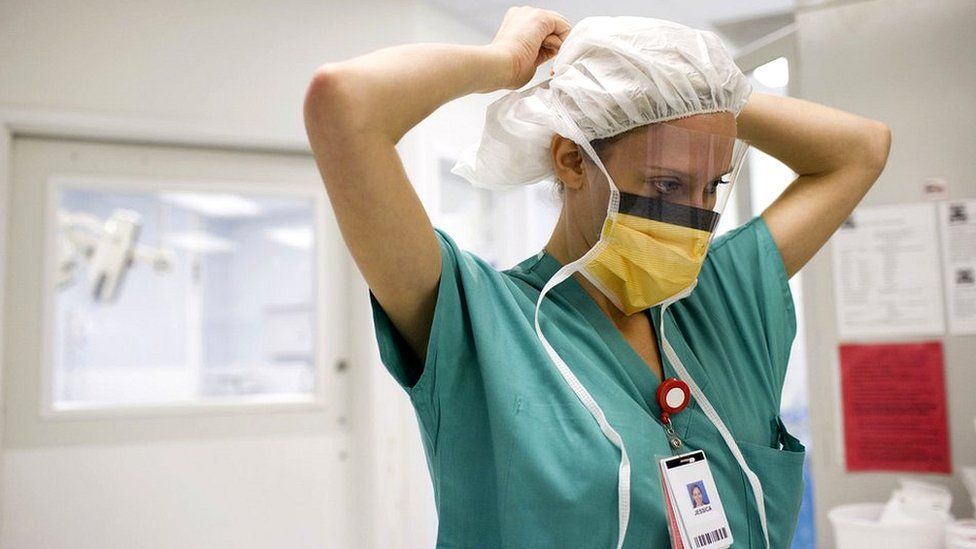 Стоковая фотография медсестры, надевающей маску