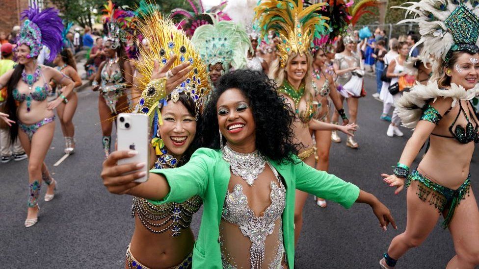 Performers dance down street and take a selfie at notting hill carnival