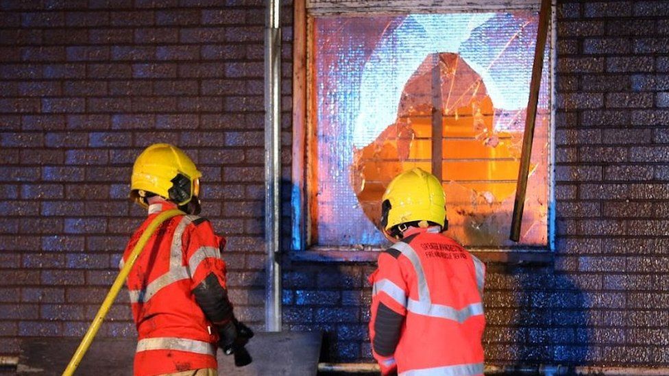 firefighters look at fore through venue window