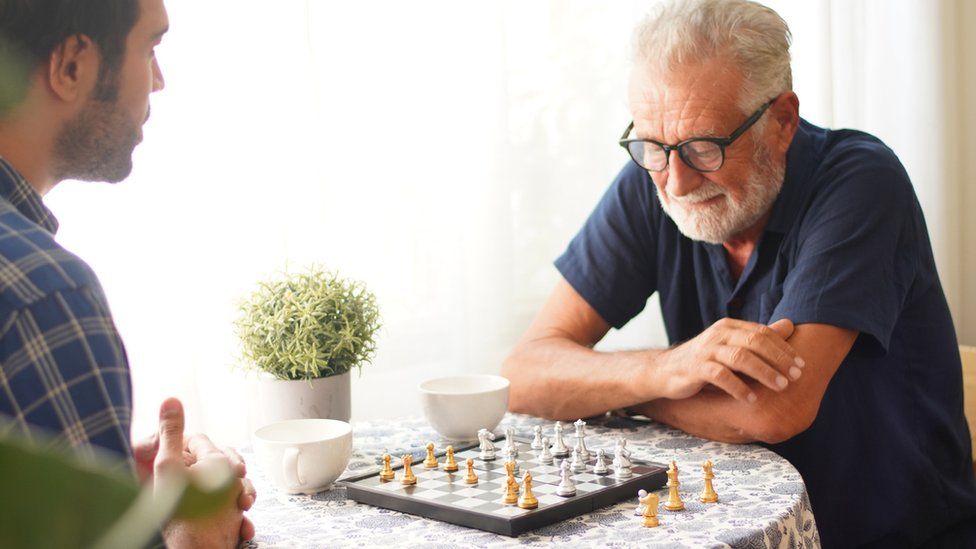 мужчина играет в шахматы со своим сыном