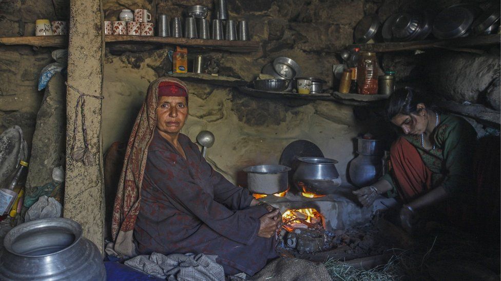 A shepherd woman poses with her daughter as they prepare lunch inside a mud house at Kousarnaag in Shopian district.