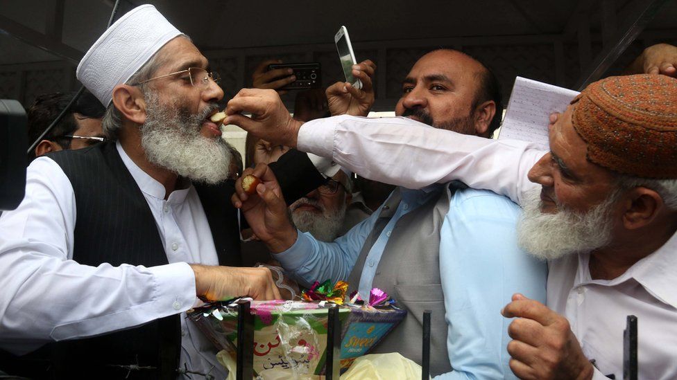Siraj ul Haq, the head of the conservative Jamaat-e-Islami group, shares sweets with opposition supporters after the Supreme Court verdict to disqualify Pakistan's PM Nawaz Sharif, 28 July, 2017