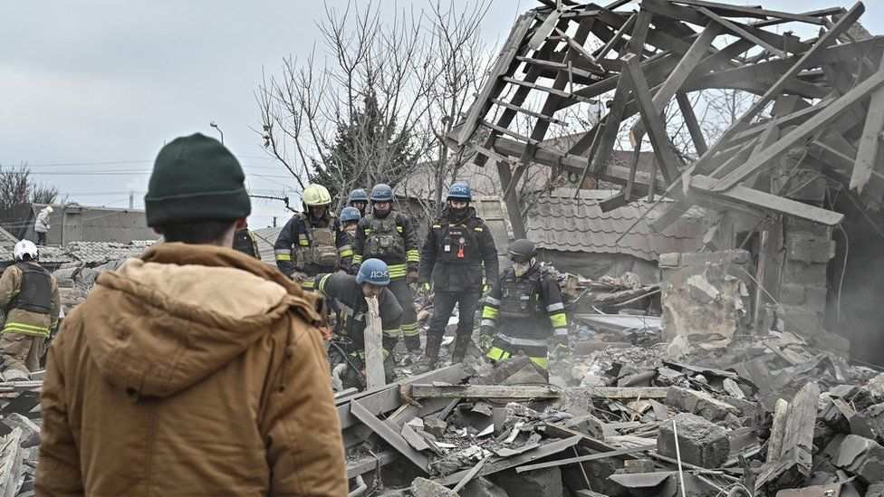 A local resident stands as rescuers work at the site of a Russian missile strike, amid Russia's attack on Ukraine, in Zaporizhzhia, Ukraine December 29, 2023