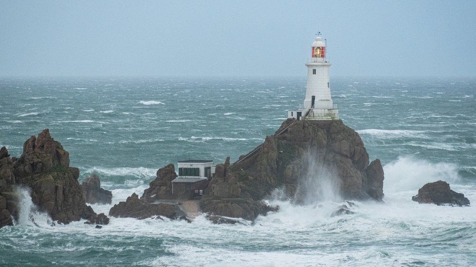 Waves crash around the lighthouse at La Corbiere