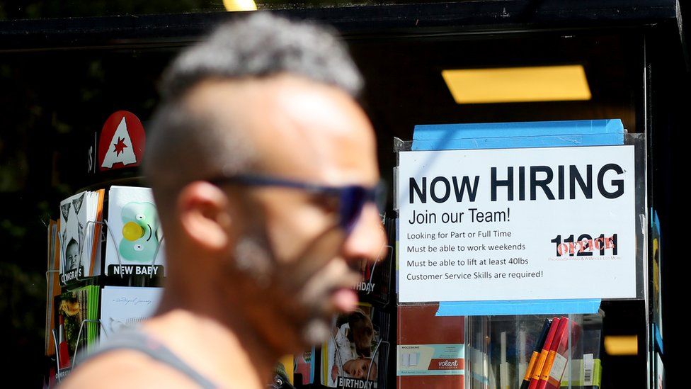 A man in front of a hiring sign