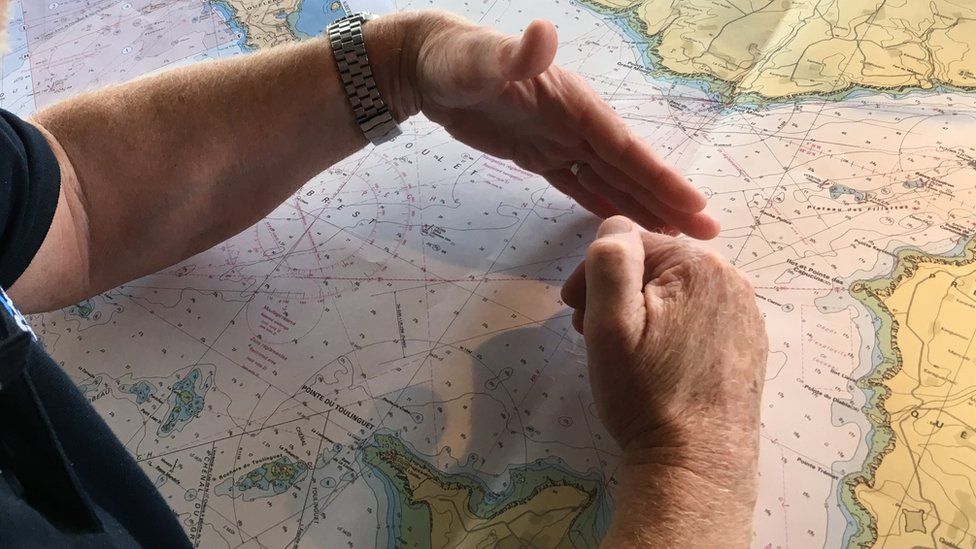 L'hour's hands in close up, framing an area of water on a map