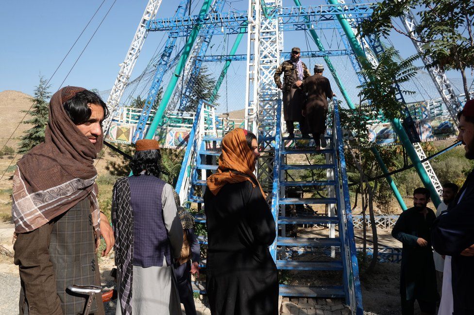 Armed Taliban fighters wait to board a pirate ship for a swing in Qargha recreational park on the western suburb of Kabul City on September 17, 2021 in Kabul, Afghanistan.