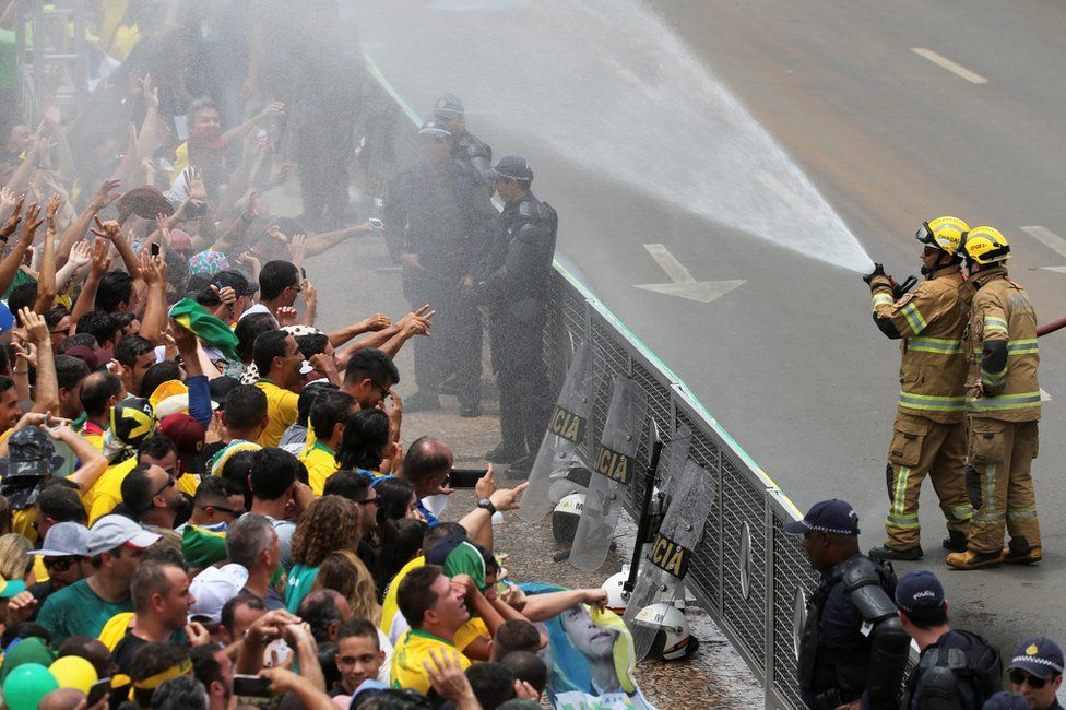 Firefighters spray water on supporters of Jair Bolsonaro outside the Planalto Palace, 1 January
