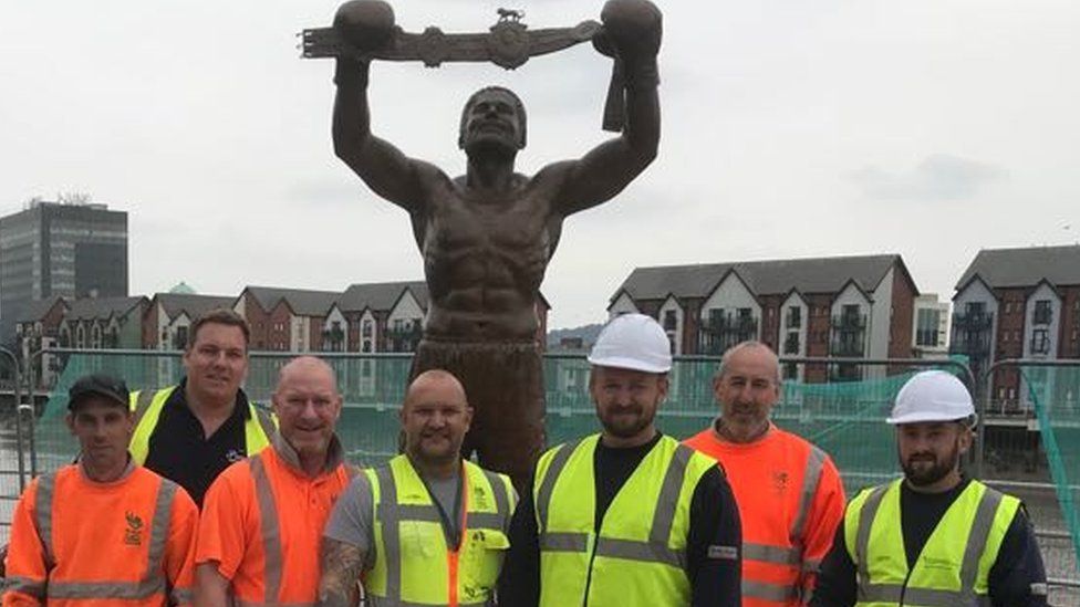 The David Pearce statue in Newport with the workers who constructed it