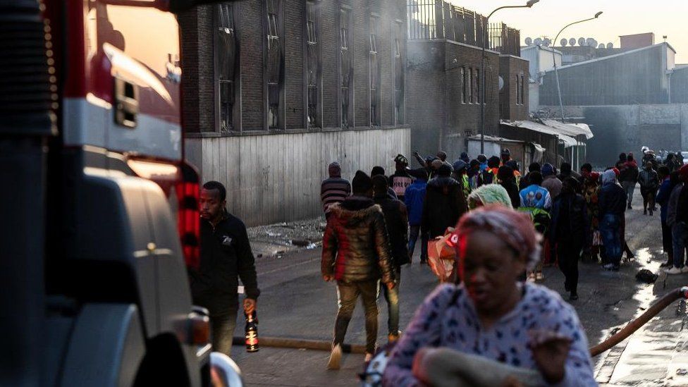 People walk past a burnt building in Johannesburg, South Africa