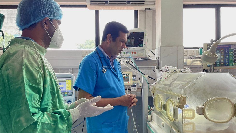 A Sri Lankan doctor stands with his attendant beside an incubator containing a premature baby