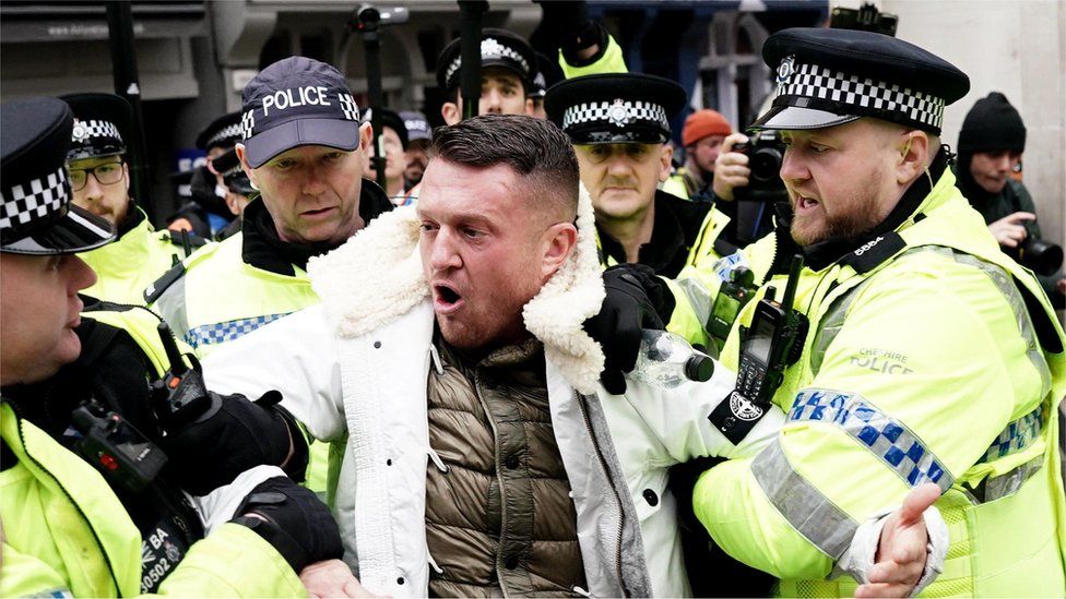 Tommy Robinson being led away by police officers at the march in central London on Saturday