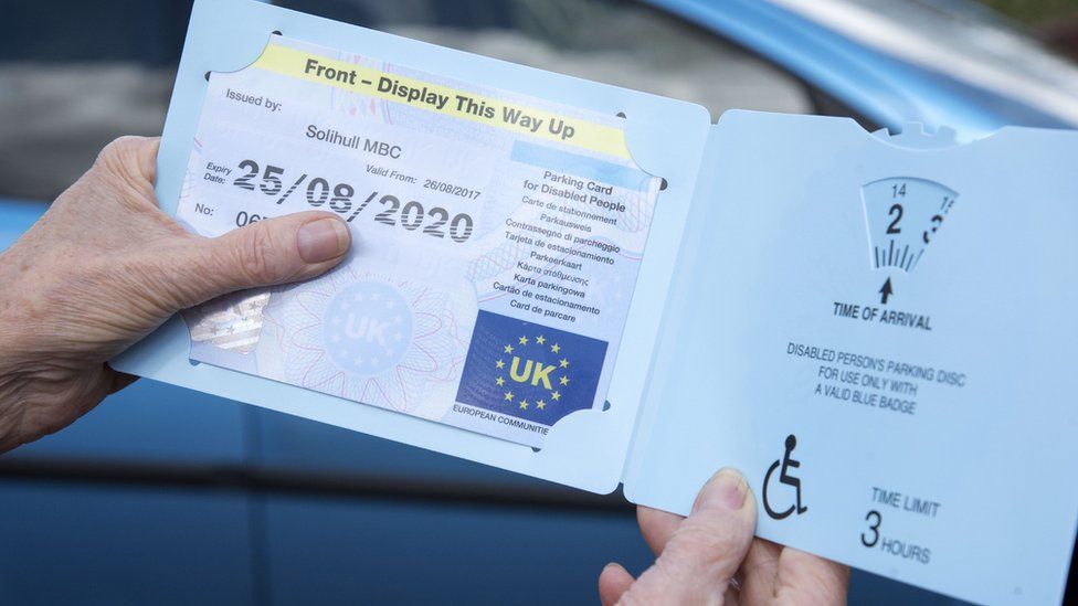 A woman showing her disable person's parking permit