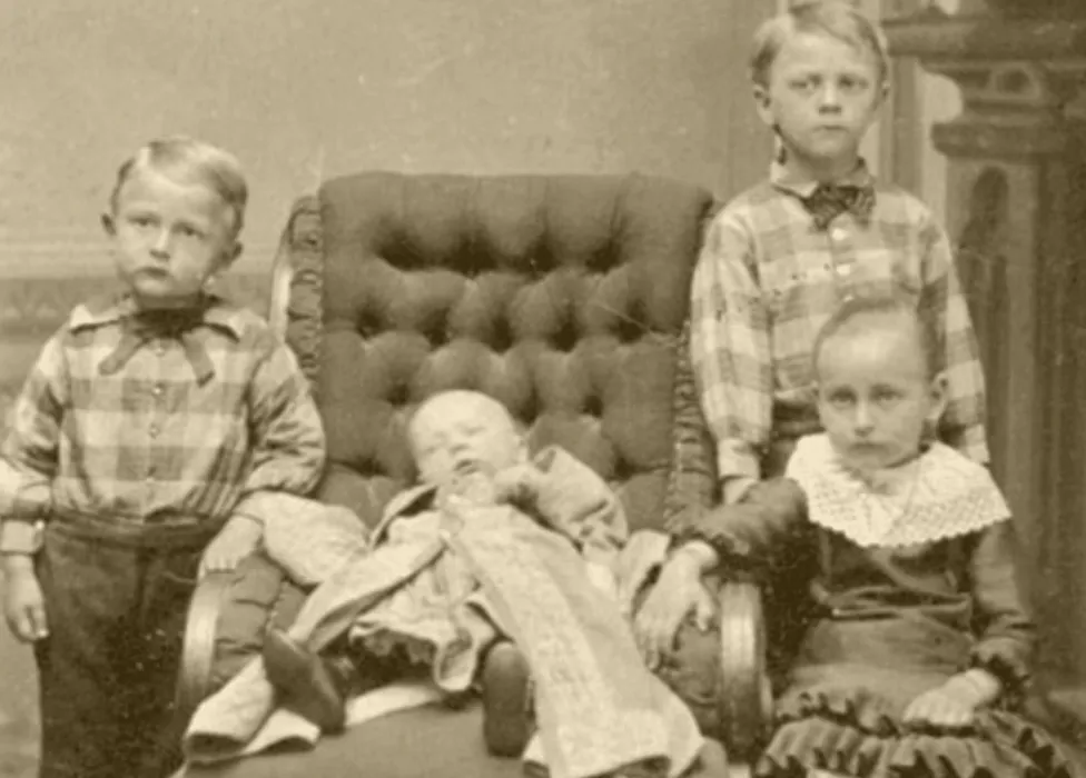 Victorian children pose around their deceased sibling