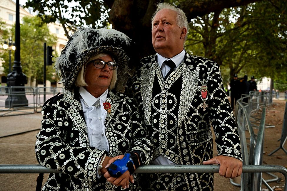 A Pearly King and Queen line the Procession Route in London on September 19, 2022, ahead of the State Funeral Service of Britain's Queen Elizabeth II. - Leaders from around the world attended the state funeral of Queen Elizabeth II. The country's longest-serving monarch, who died aged 96 after 70 years on the throne, was honoured with a state funeral on Monday morning at Westminster Abbey. (Photo by Louisa Gouliamaki / AFP) (Photo by LOUISA GOULIAMAKI/AFP via Getty Images)