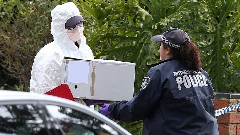 Investigators carry a box of evidence from the house gunman Yacqub Khayre is believed have shared with his mother
