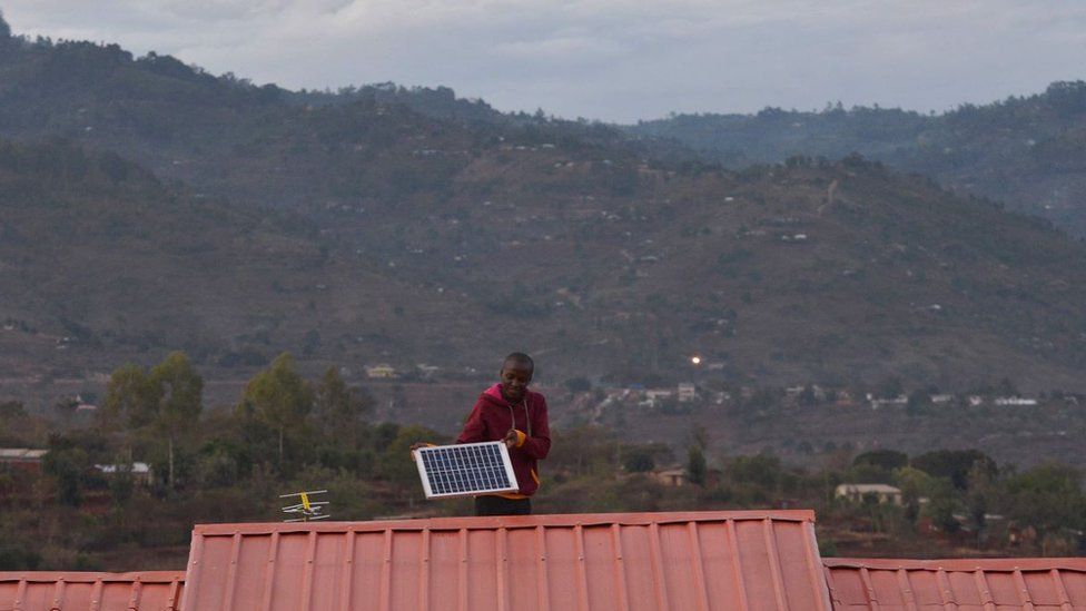 A man adjusts a solar panel on his roof at dusk in the villqge of Kwa-Mutisya in Machakos county, some 100 kilometres southeast of Nairobi, on November 16, 2016.