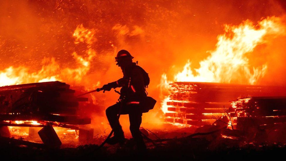 A firefighter douses flames as they push towards homes in California, 7 September 2020