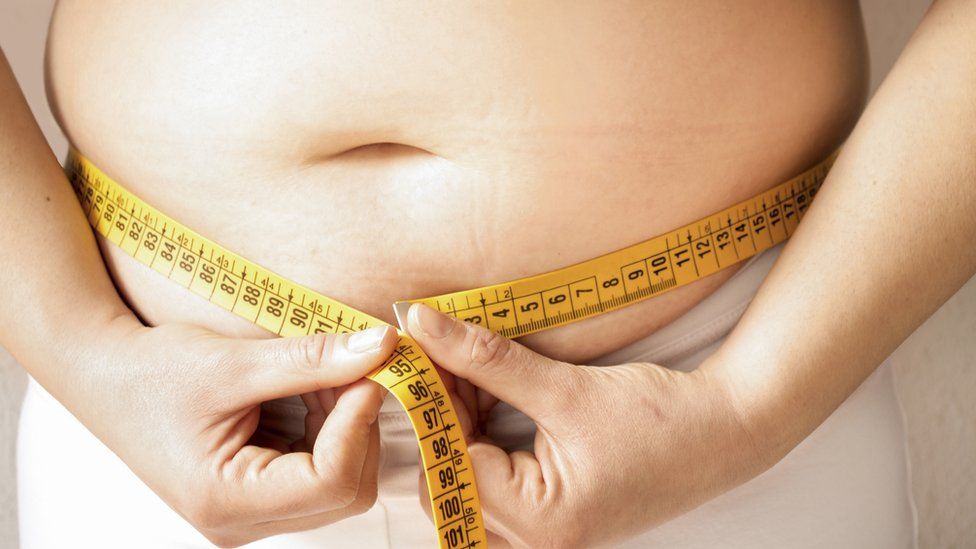 A teen measuring their waistline