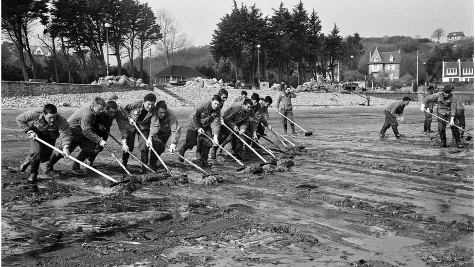 Soldiers clean up oil slick, on April 16, 1967 on the beach of Perros-Guirec