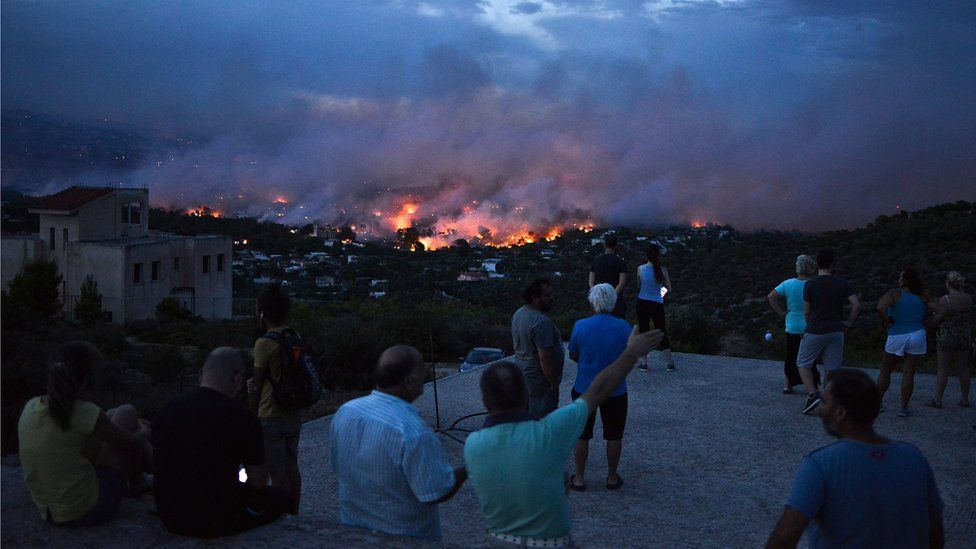 People watch a wildfire in the town of Rafina, near Athens, on July 23, 2018.
