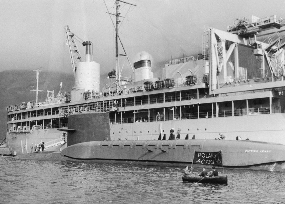Mar. 03, 1961 - DEMONSTRATIONS AS POLARIS SUBMARINES ARRIVES ...LOCH... The 6700 tom American Polaris submarine PATRICK HENRY arrived in the Holy Loch-Firth of Clyde today-and tied up alongside the Submarine Depot Ship ''Proteus''...On arrival she was checred by the Royal Navy and demonstrators the vessels...One lone demonstrator in a small cance-dodgod police launches for some time but eventually he capsized and had to be fished out of the water by naval frogmen - Image ID: E0W3NX