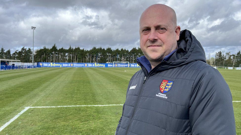 Stephen Boyle, on the pitch at Humberdoucy lane, wearing a Wanderers coat