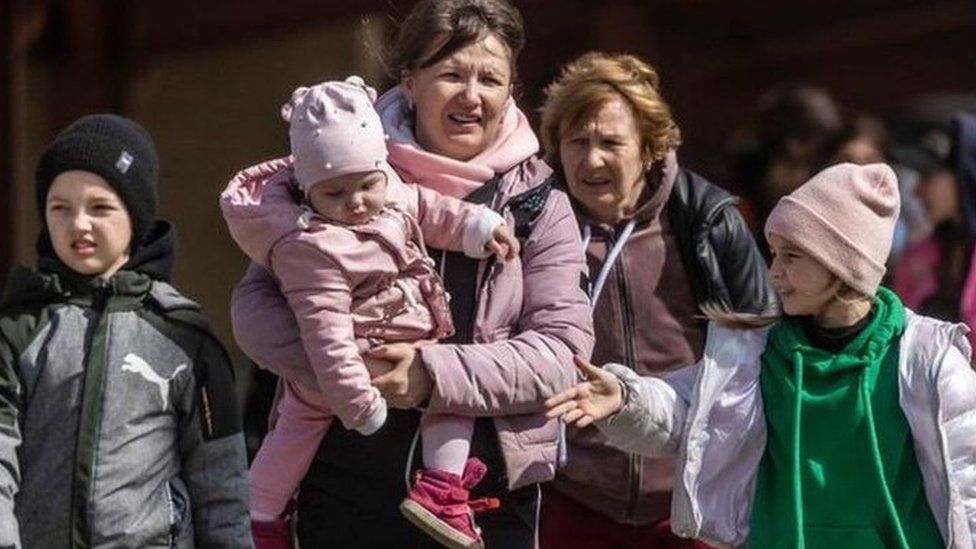 Ukrainian refugees walking on train platform in Poland