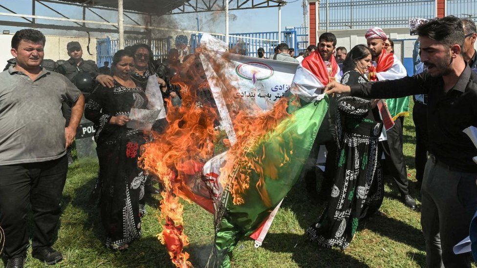 Protesters burn an Iranian flag