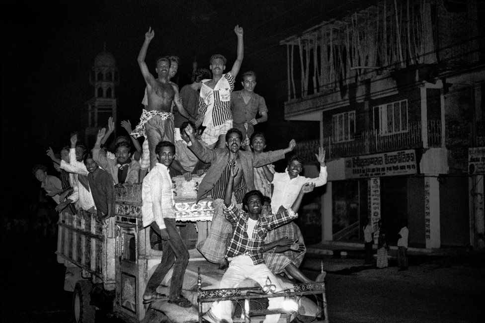 People cheering on a the back of a vehicle