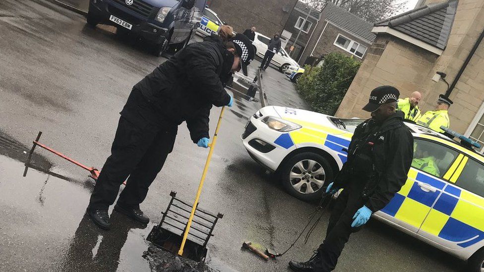 Police examine a drain in Corby old village