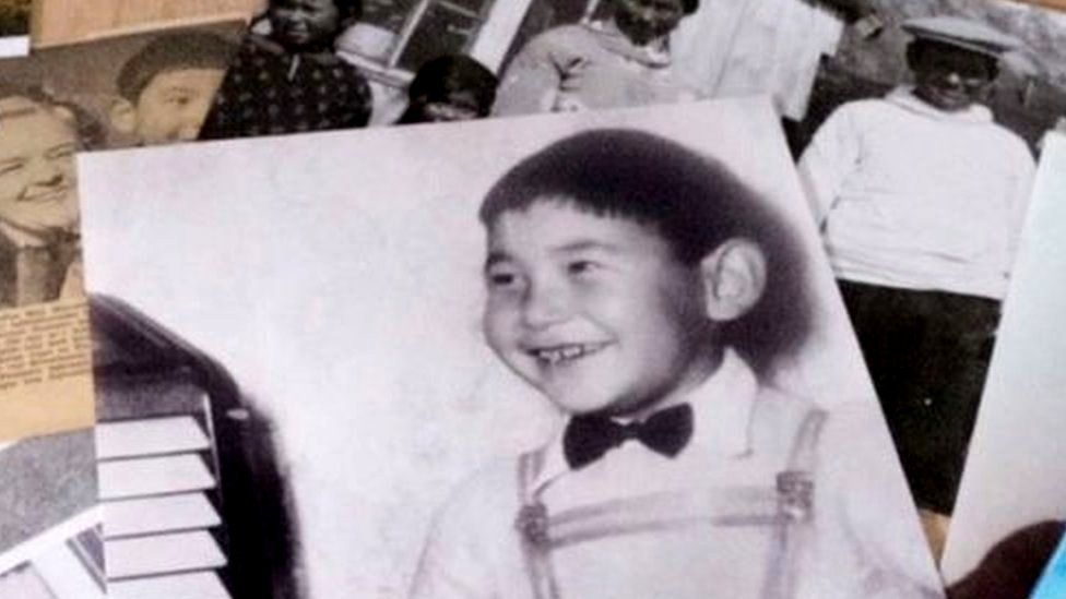 Historic photos of Gabriel Schmidt as a child are strewn across a table