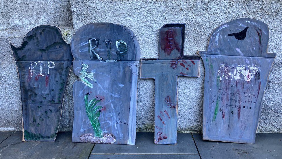 four fake gravestones made from cardboard and painted grey with fake moss and 'RIP' written on them