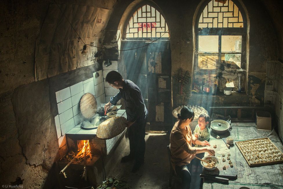 Family preparing food indoors, with rays of sunlight shining through the windows