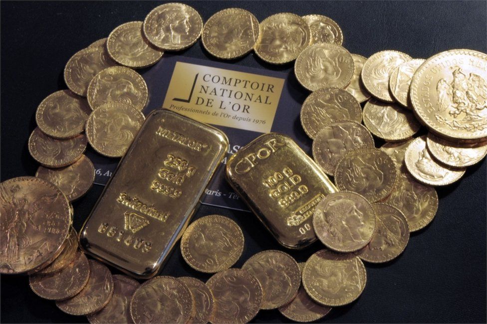 A picture showing gold bars and coins on a table at the Comptoir National de l'Or, a shop that buys, sells and estimates gold and jewellery in Paris.